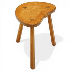 Mouseman - oak three-legged stool, dished kidney-shaped seat, raised on three octagonal splayed supports, with carved mouse signature, by the workshop of Robert Thompson of Kilburn