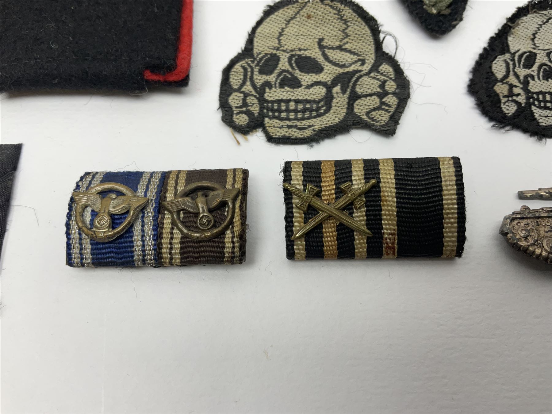 Collection of eleven German metal and cloth badges and uniform buttons including driver's badge, two 'SS' fabric skulls, private's shoulder tabs, Police cloth badge, tank destruction badge, medal bars and ribbon etc; most WW2 period