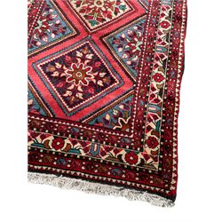 Persian Hamadan runner, red ground, decorated with eighteen lozenge medallions decorated with stylised floral motifs, three band border decorated with plant motifs and geometric patterns