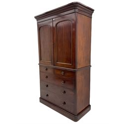 Victorian mahogany linenpress, moulded projecting cornice over two arched panelled doors, the interior fitted with two linen slides, the lower section fitted with two short and three long drawers, plinth base