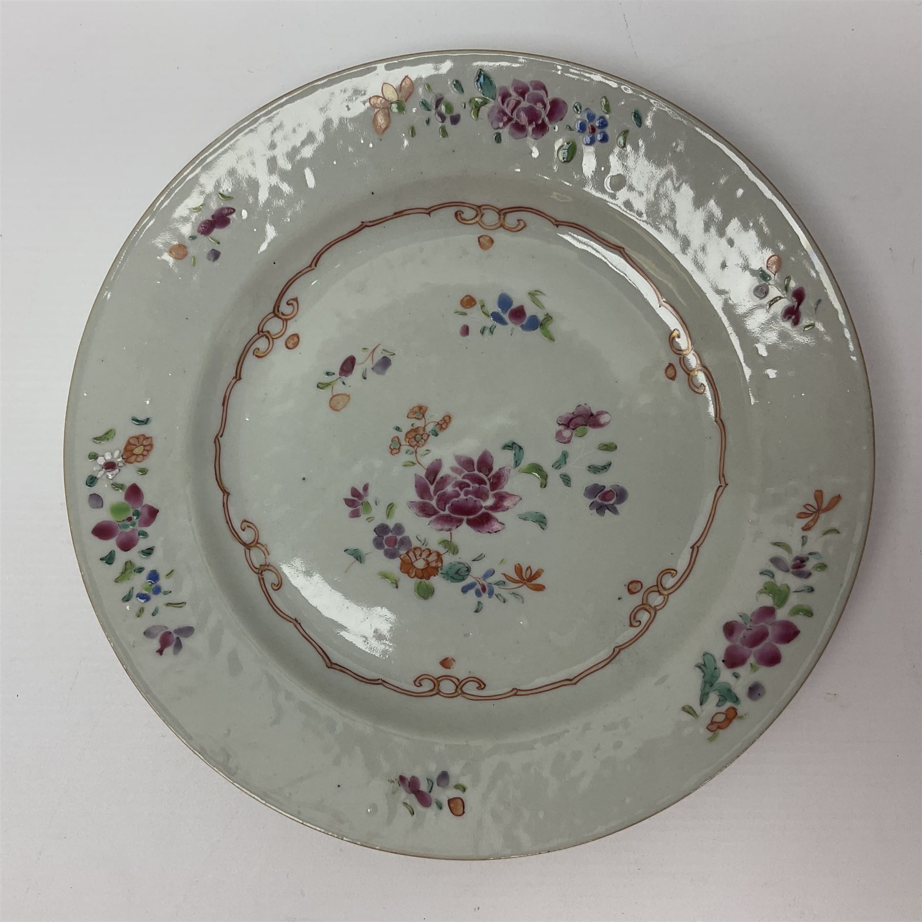 Three 18th century Chinese Famille Rose plates, the first example enamelled with blossoming peonies, rockwork and fence, the other two examples of similar design, decorated with blossoming peonies and sprigs within shaped inner borders, each approximately D23cm