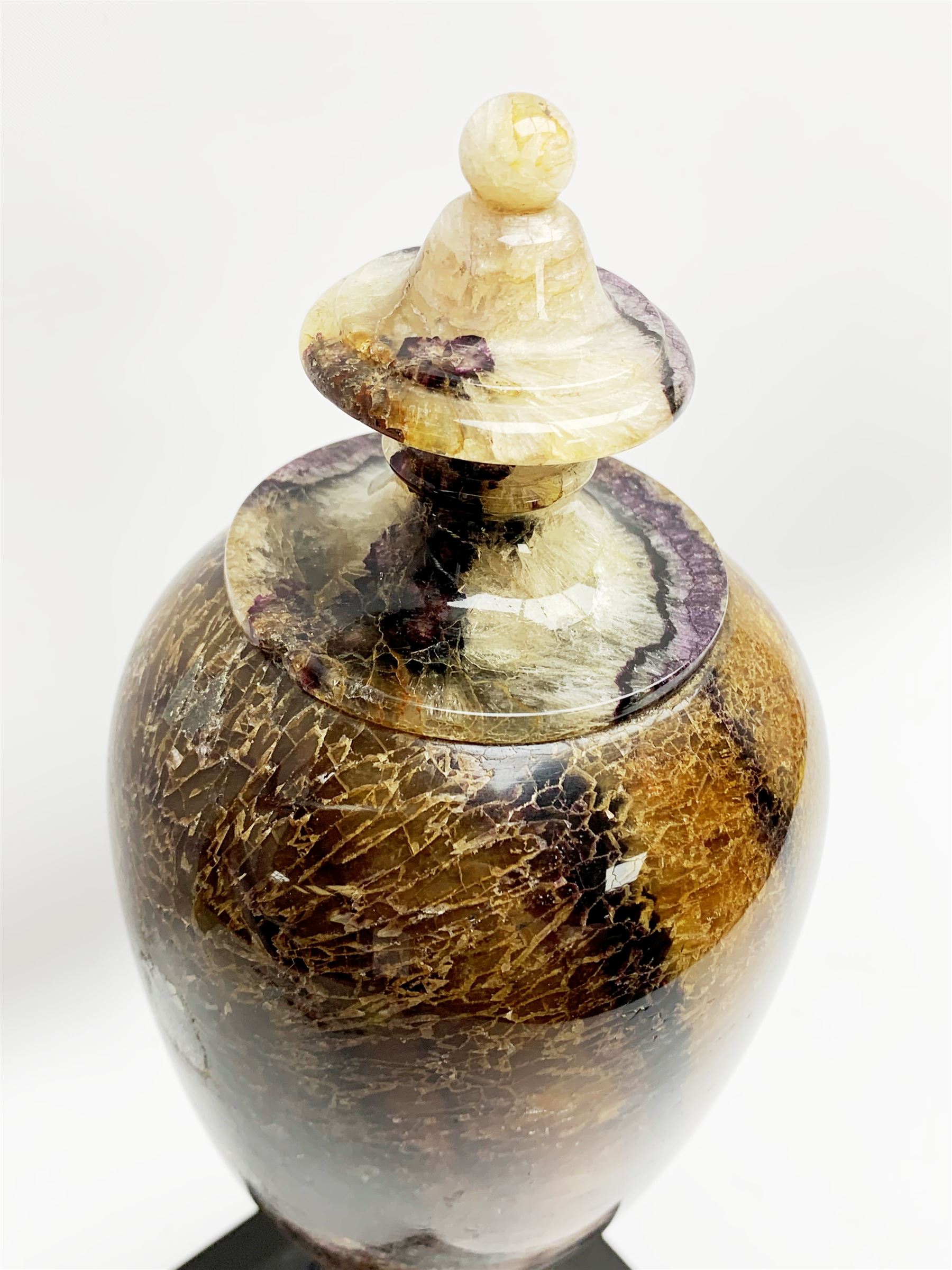 Early 19th century and later Blue John urn, Winnats one vein, of ovoid form with integrated cover and ball finial, upon a spreading circular base, and square stepped black lacquered base, H34.5cm