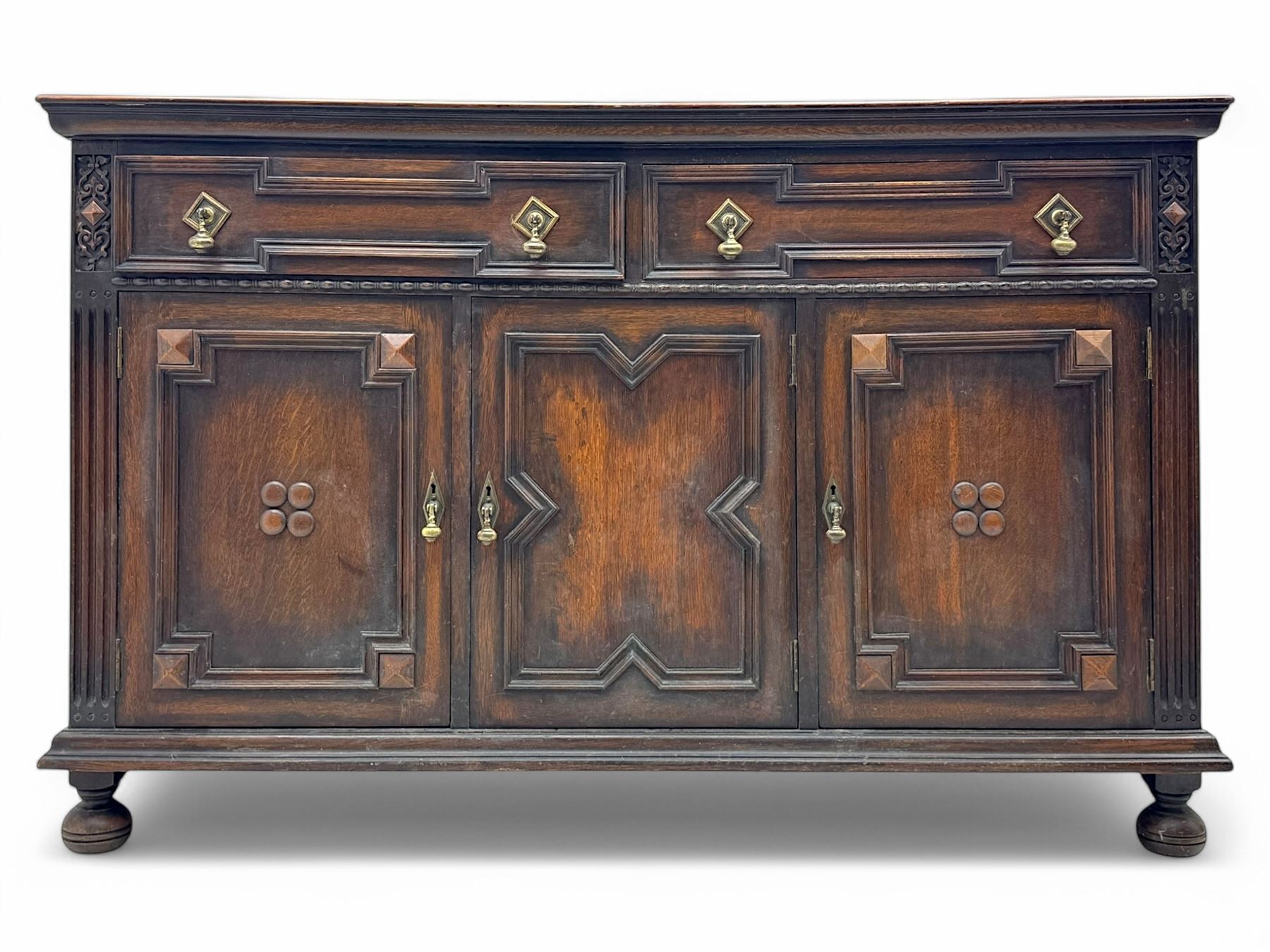 Jacobean-style oak dresser base with two frieze drawers above three cupboards with panelled and moulded decoration, fitted with drop handles, supported on bun feet, circa 1900