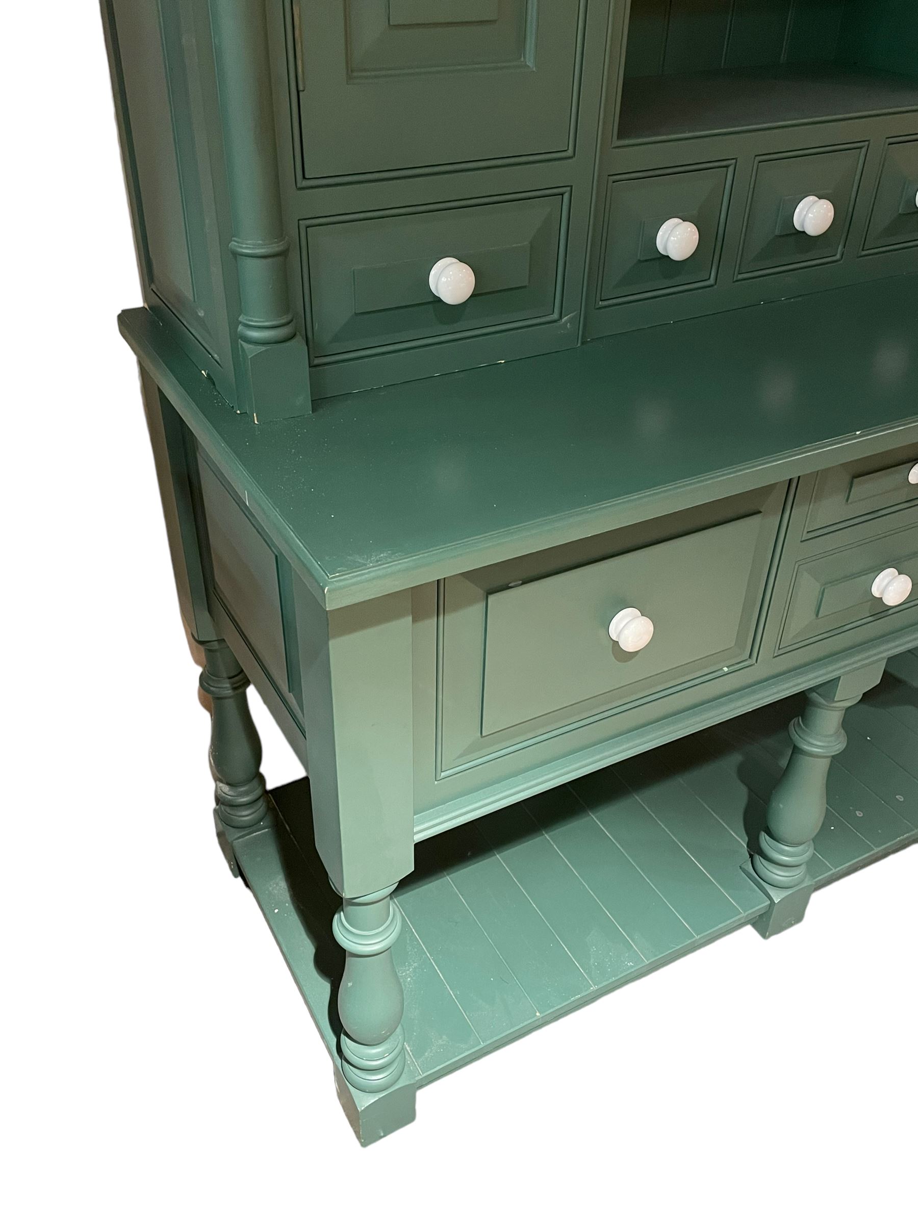 Large contemporary teal green painted kitchen dresser, projecting cornice over three open shelves flanked by cupboard with five spice drawers below, the base fitted with four assorted drawers, raised on turned vasiform supports united by undertier