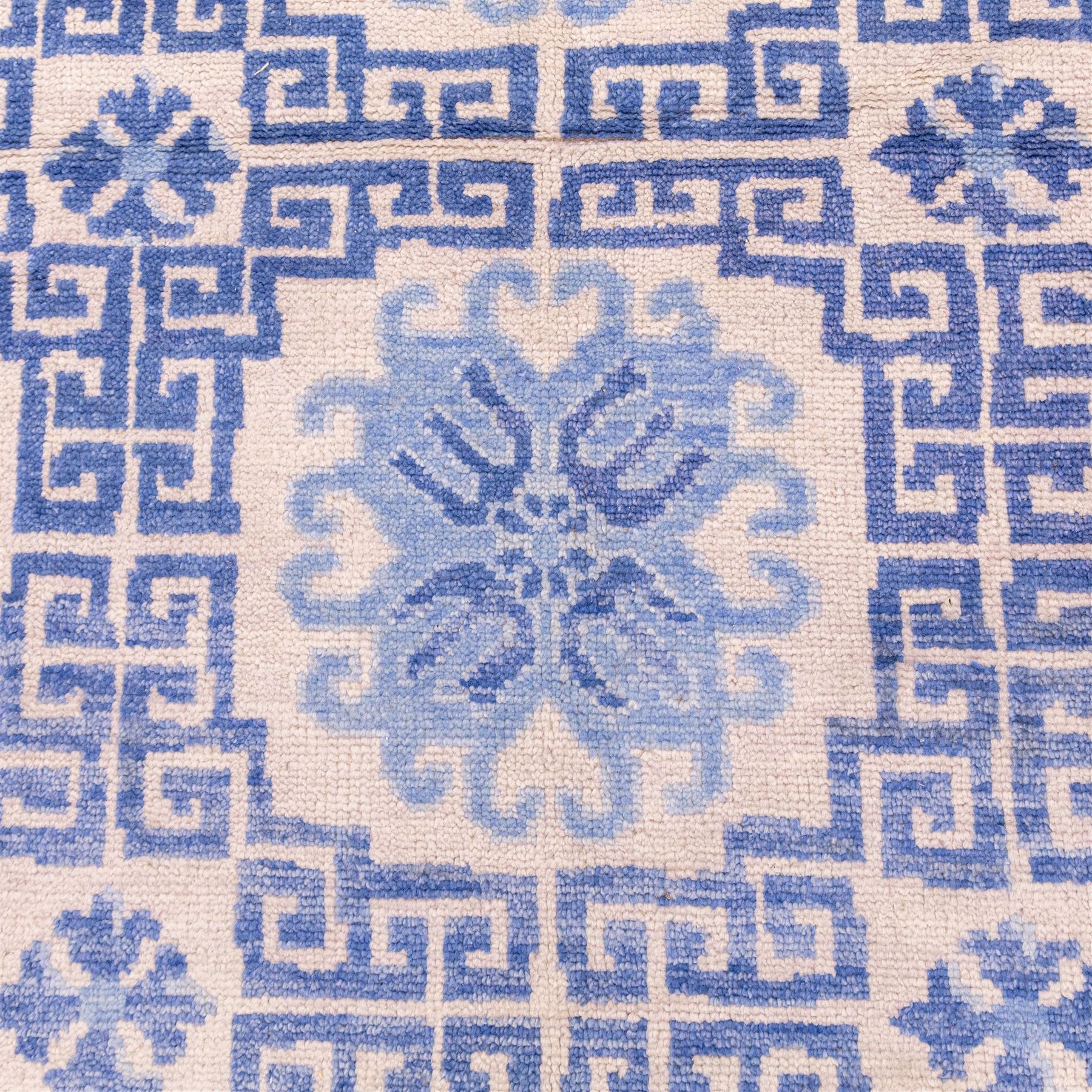 Late 20th century Chinese hand-woven wool carpet, ivory field with a lattice of stylized lotus medallions, contained within geometric key fret panels interspersed with a small floral device enclosed within a complementary Greek-Key border, the designs in tones of pale blue and soft cream