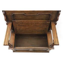 Early 20th century oak monks bench, panelled back converting to a table top, reeded armrests with barley twist uprights, hinged seat over panelled base supported on bun feet