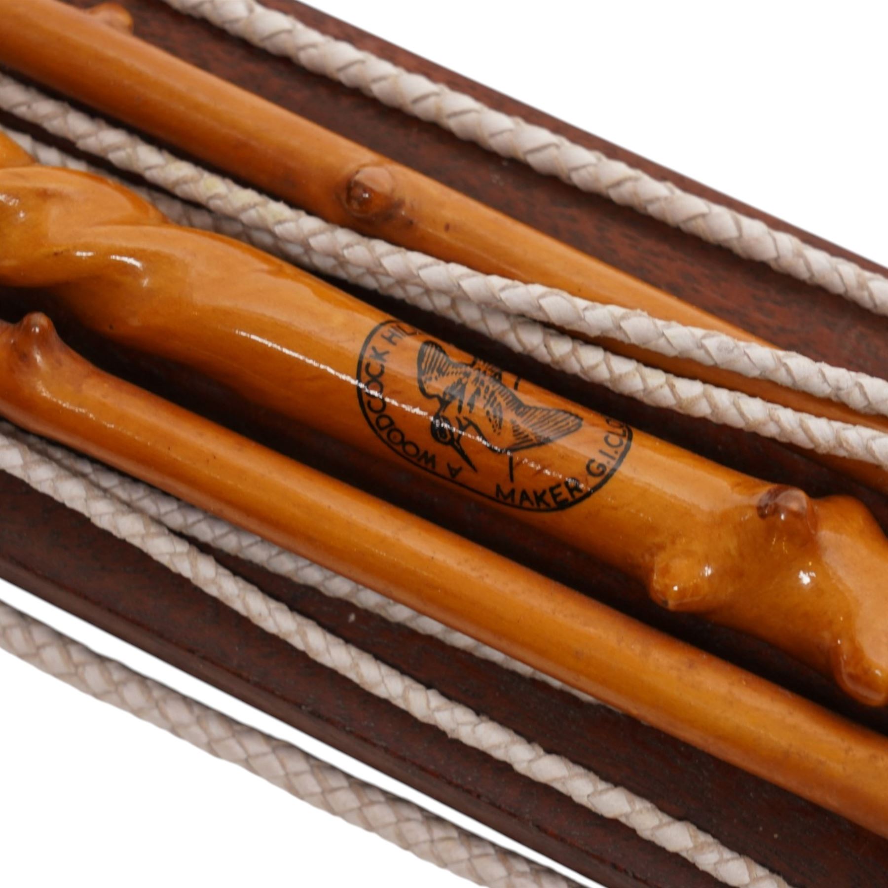 A Woodcock Hill - 20th century travelling coaching whip, the two part yew wood twisted shaft, with leather grip and brass collar and butt cap, with makers mark below the leather handle 'A Woodcock Hill Whip Maker G.I Clothier', together with an additional thong end, mounted upon a wall mounted holder, whip 142cm 