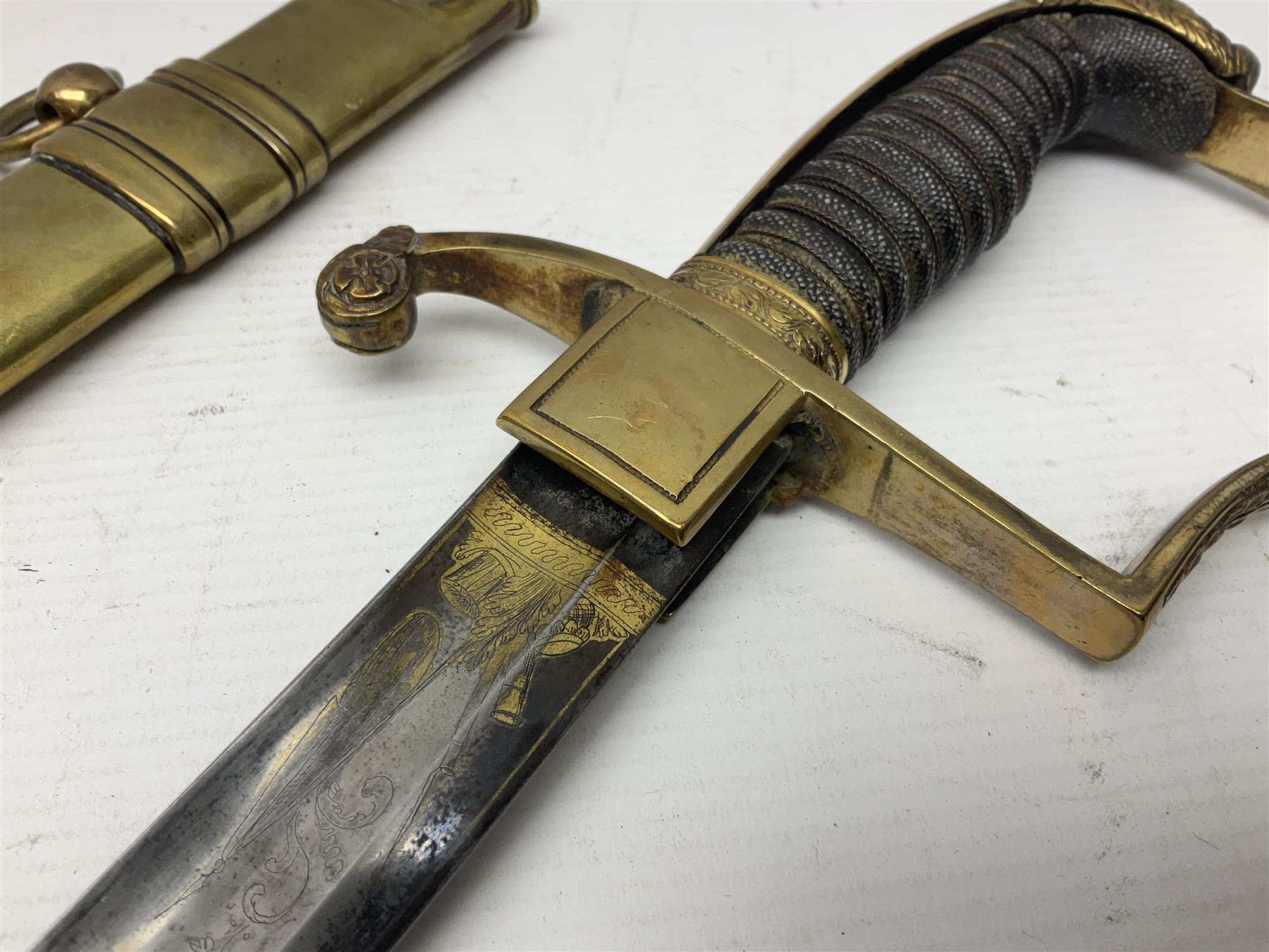 German Saxon 1st Empire Light Cavalry officer's sword c1820s, the 79cm clipped curving blade engraved with the crest of Hanover and various battle trophies with traces of blueing and gilding, brass hilt with knucklebow, foliate square langets, ornate downswept quillon, wire-bound fish skin grip with lion's head pommel; in brass scabbard with two suspension rings L95cm overall