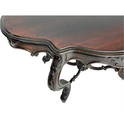 19th century Irish rosewood centre table, the shaped and moulded top over shaped apron carved with scrolled foliage, on serpentine supports carved with bell flowers, the supports united by anthemion carved finial and s-scroll x-framed stretchers