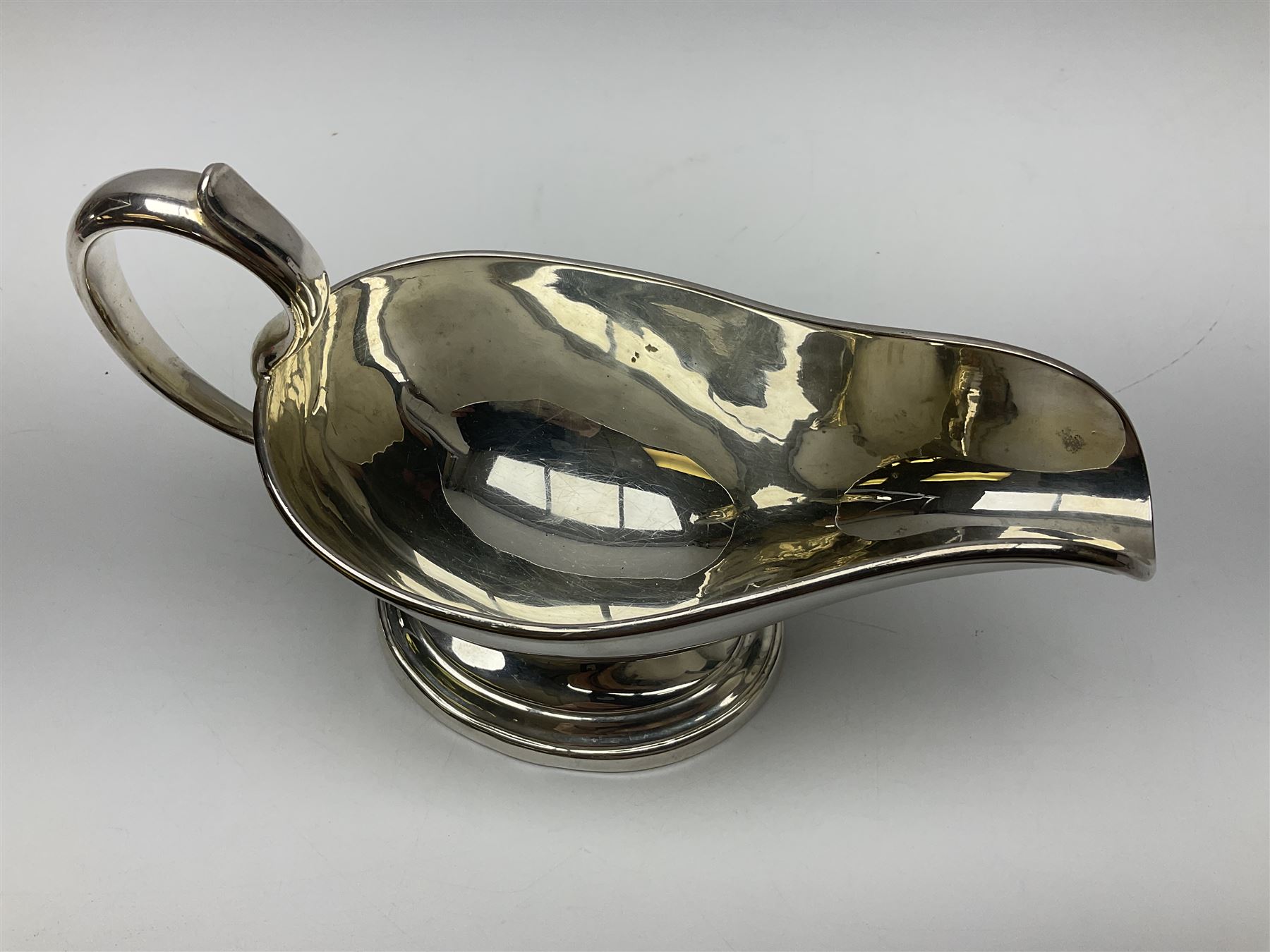 Christofle silver-plated sauce boat, of typical plain form, with capped C scroll handle and engraved anchor crest to body, upon a stepped oval foot, stamped 22 Christofle to base, including handle H14cm