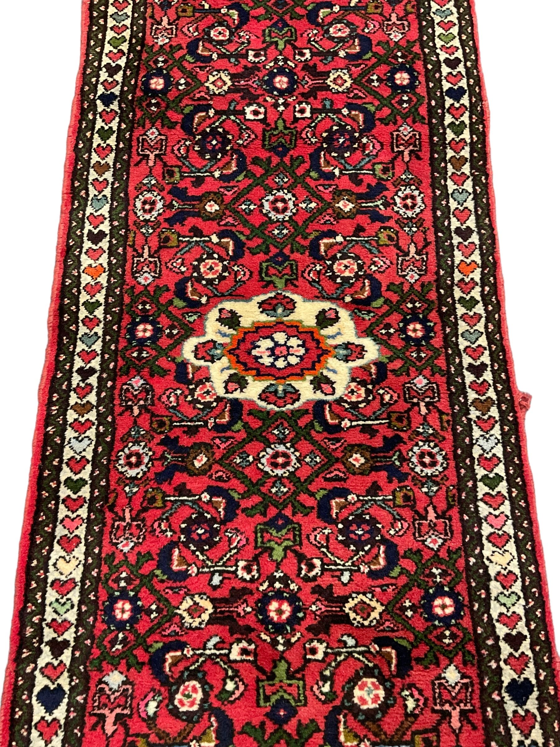 Persian red ground runner, decorated with large Herati motifs and shaped central medallion, the guarded border decorated with repeating heart motifs
