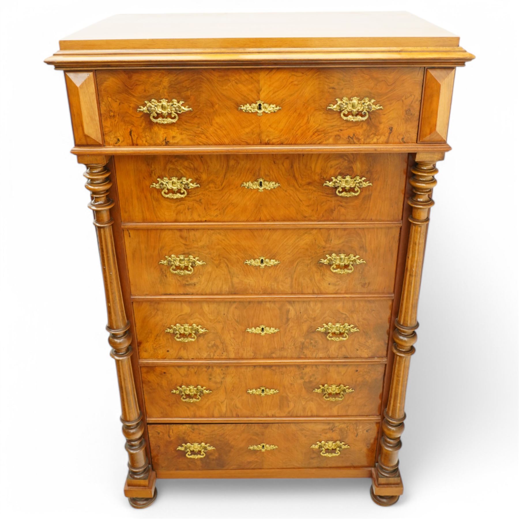 Tall late 19th century walnut chest, stepped and moulded top over six drawers, ornate cast gilt metal handles, enclosed by turned and fluted upright columns, on turned front feet 