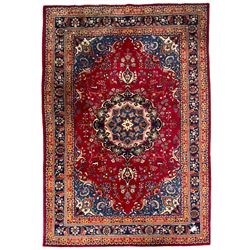 Persian Meshed red ground rug, central floral rosette medallion surrounded by trailing branch and stylised flower heads, repeating scrolling border