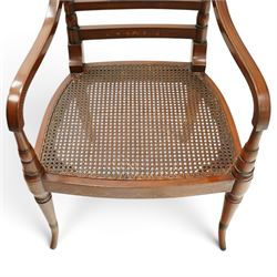 Pair of Sheraton Revival painted mahogany open armchairs, scrolled cresting rail with floral painted decoration over a double-caned back and rose-branch painted back bar, cane seat over C-scroll-painted seat rail, on splayed tapering supports, with all-over painted ebony faux stringing