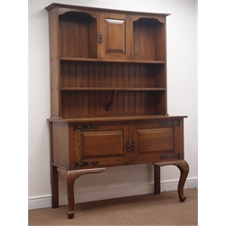  Early 20th century oak Arts & Crafts dresser, projecting cornice above panelled cupboard and two tier plate rack, panelled double cupboard, cabriole supports, W139cm, H190cm, D51cm  