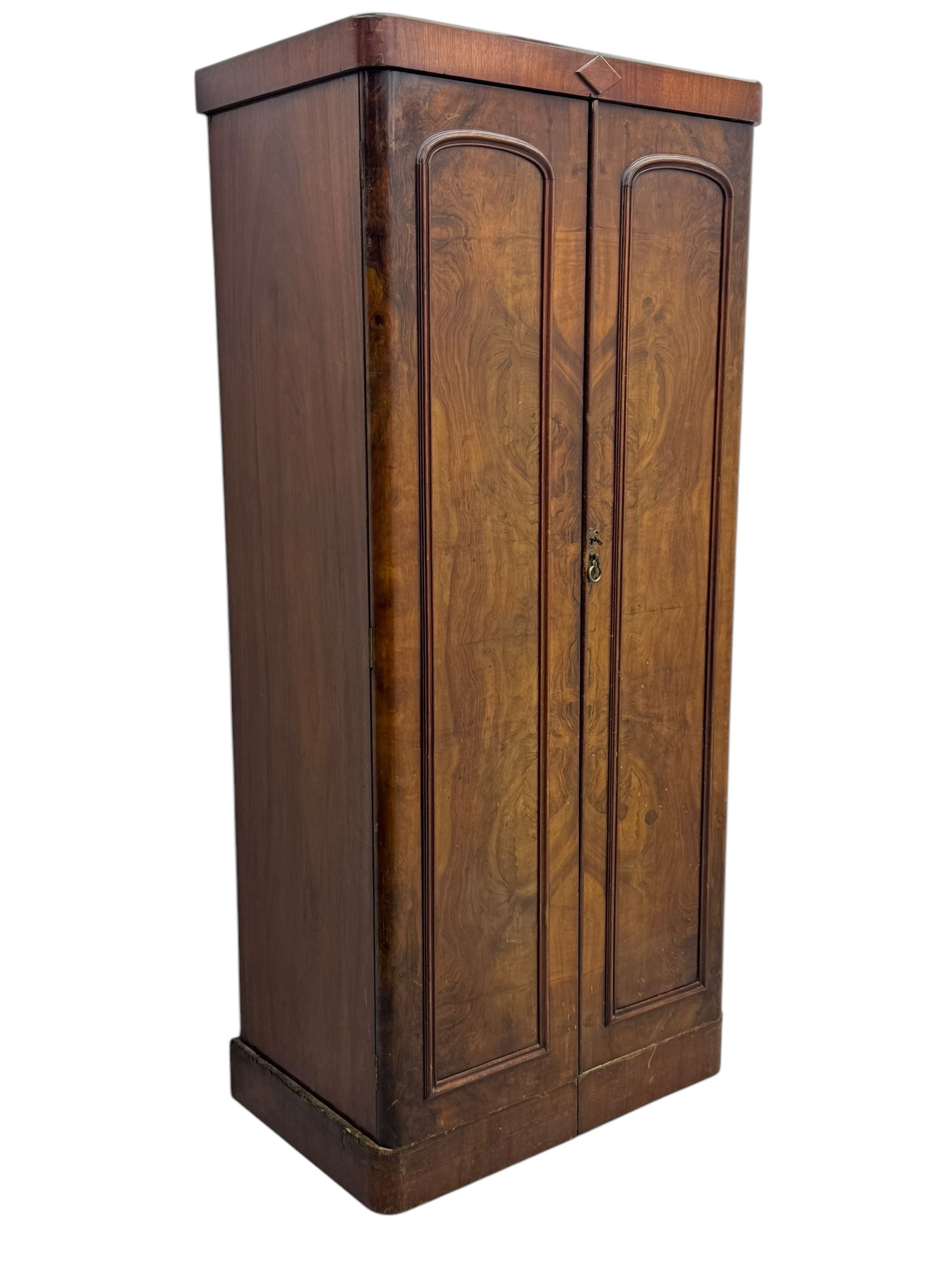 Victorian figured walnut single wardrobe, the moulded cornice with a central diamond motif over a pair of arched panelled doors with striking book-matched veneers, enclosing a fitted interior with hanging rail and hooks, on a plinth base