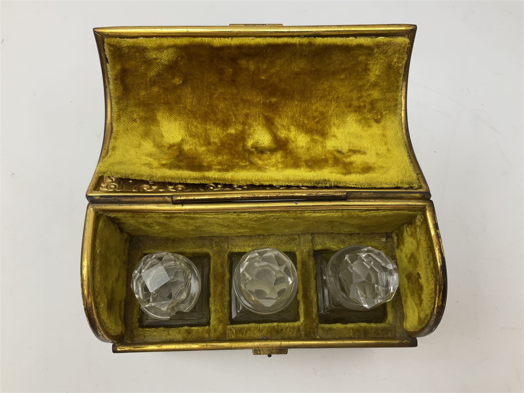 19th century brass repoussé perfume box, the ornately decorated casket with hinged domed cover lifting to reveal gold velvet lined interior containing three glass scent bottles, H14cm W15cm D7cm