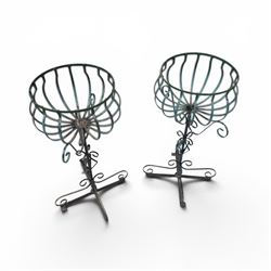 Matched pair of antique metal plant stands, each with circular strapwork basket tops, the scrollwork supports raised on an X-form base, in green painted finish with rustic patina