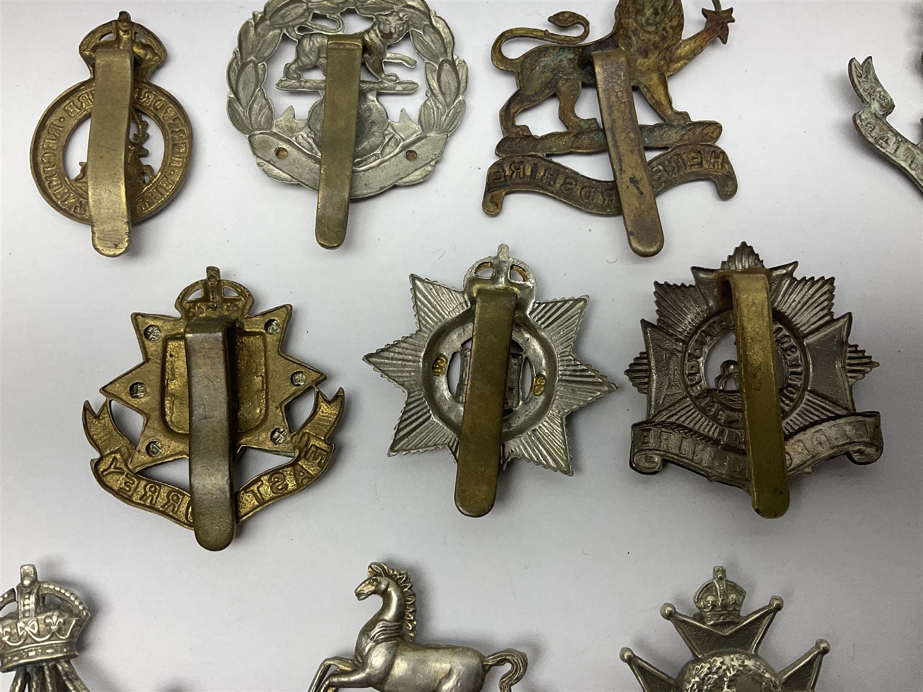 Twenty cap badges including Hertfordshire, Royal Sussex, Cambridgeshire, Hampshire, Notts and Derby, East Surrey, Herefordshire, South Lancashire, Devonshire, Bedfordshire, Durham Light Infantry etc (20)