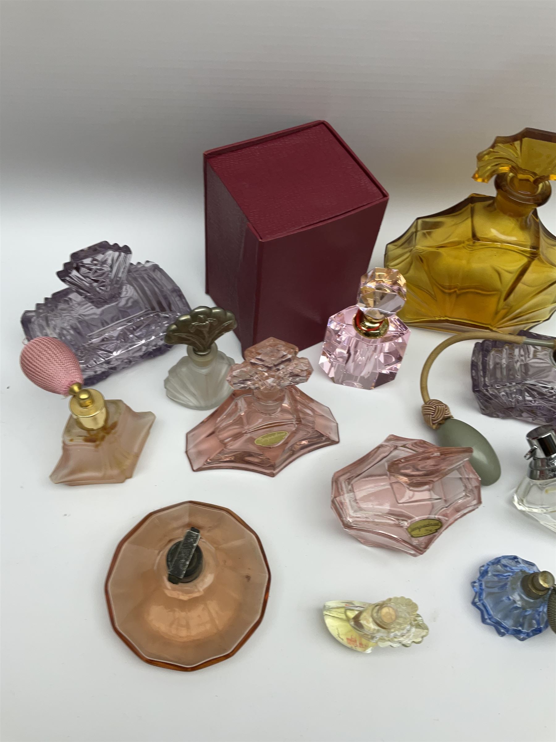 Art Deco style glass perfume bottles and atomisers, to include a large amber example with stopper of fan shape, H18cm, green glass examples with metal stoppers, and a number of other Art Deco style coloured bottles of geometric form with stoppers and mounts