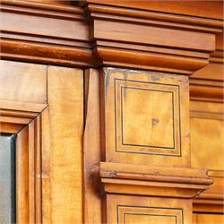 Victorian neoclassical style satinwood triple-section wardrobe, the central mirror section and arched pediment with carved monogram flanked by two panelled crossbanded doors, revealing two drawers and grooves for shelves, the hanging cupboards each with a single drawer, the whole supported on a plinth base