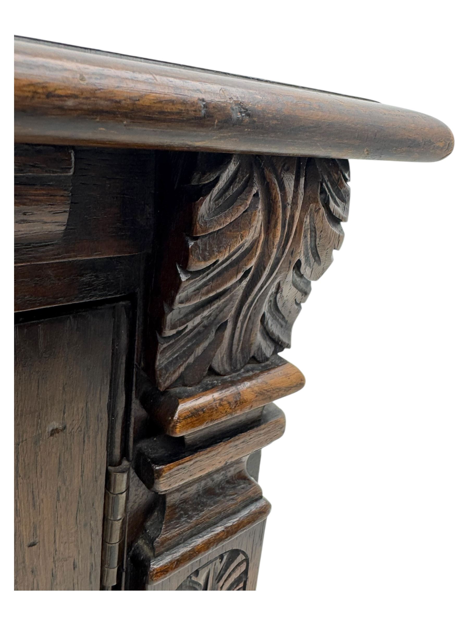 Jacobean design carved oak two door cupboard, the frieze and twin cupboard doors carved with arcaded panels and stylised foliage, raised on baluster supports united by an undertier