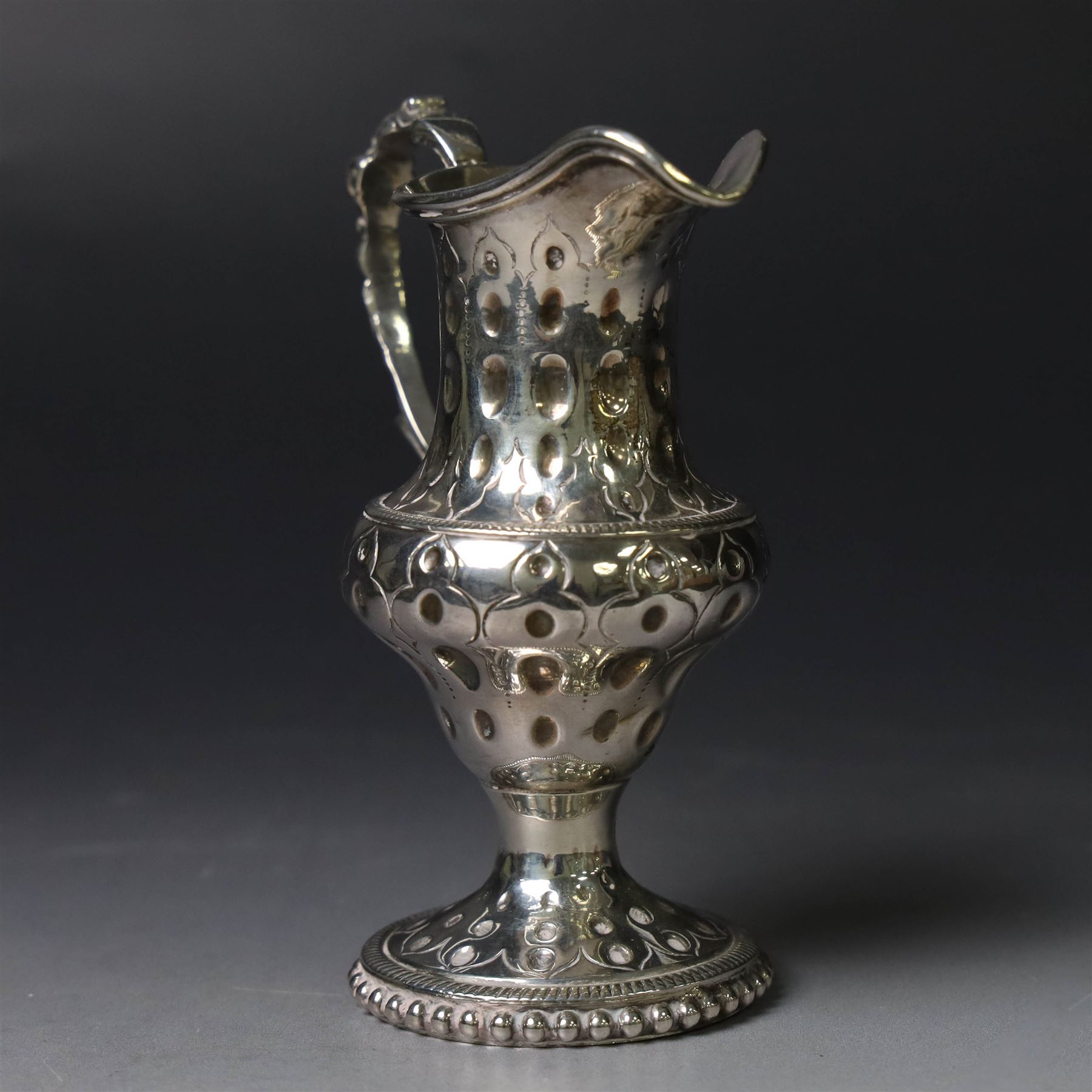 George III silver cream jug, of baluster form with hammered dimpling throughout and scroll handle, upon circular spreading foot with beaded edge, hallmarked Thomas Shepherd, London 1784, H10cm
