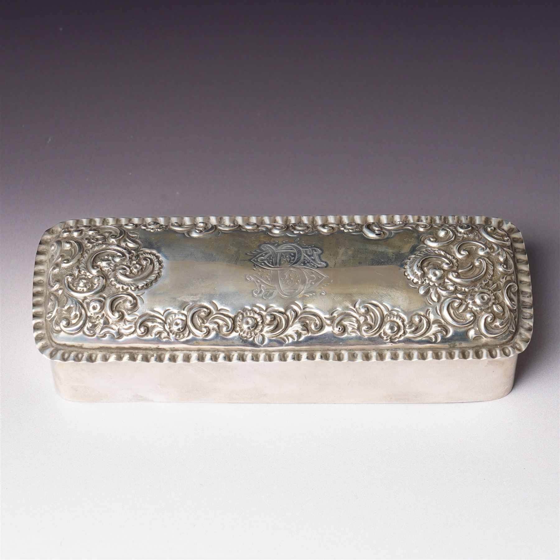 Late Victorian silver dressing table box of rectangular form with embossed hinged lid and engraved with a monogram with crimped border W15.5cm Chester 1896 Maker King & Sons