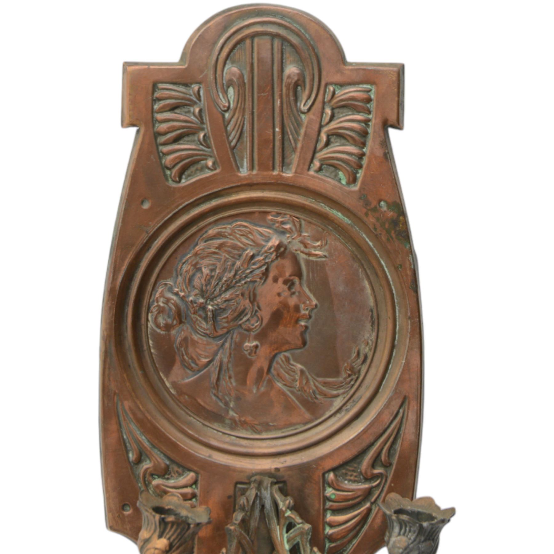 Pair of late 19th/early 20th century Art Nouveau copper twin branch wall sconces, each with shaped back plate chased with a central panel of a maiden in profile above and surmounted by foliate motifs, supporting two foliate open cast branches with bud sockets above conforming drip pans, H31cm W16cm D8.5cm
