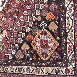 Southwestern Persian Qashqai rug, central diamond medallion with hooked motifs flanked by four corner medallions on a rich red madder field with dark brown ground of stylized floral and animal motifs, and ivory border with alternating floral palmettes and a red main  border with a meandering vine pattern 