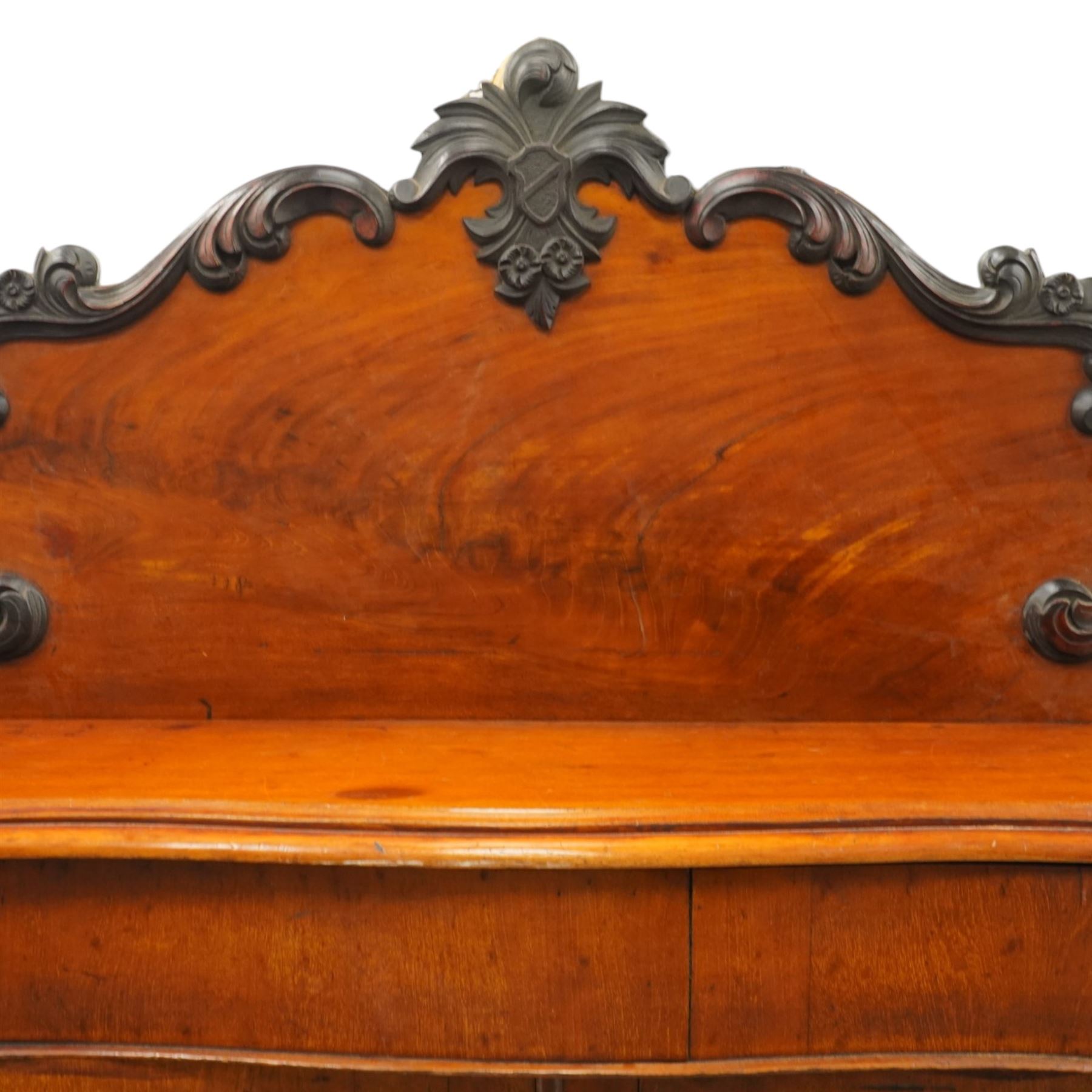 Victorian mahogany chiffonier, raised back with applied carvings, above a serpentine fronted base, a single frieze drawer, above a cupboard with shelf and drawer with campaign handle, raised on a plinth base