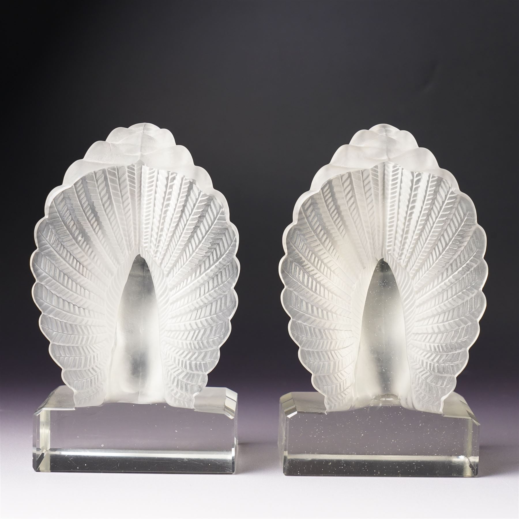 Pair of frosted glass peacock bookends, in the style of Lalique, on clear bases with bevelled edges, H15cm