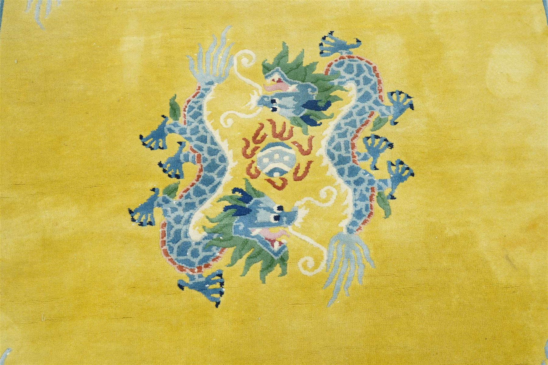 Modern Chinese hand-knotted wool pile carpet, golden field decorated with conforming dragons amidst stylized cloud scrolls enclosed by a Greek gey meander border, with cotton fringe ends 