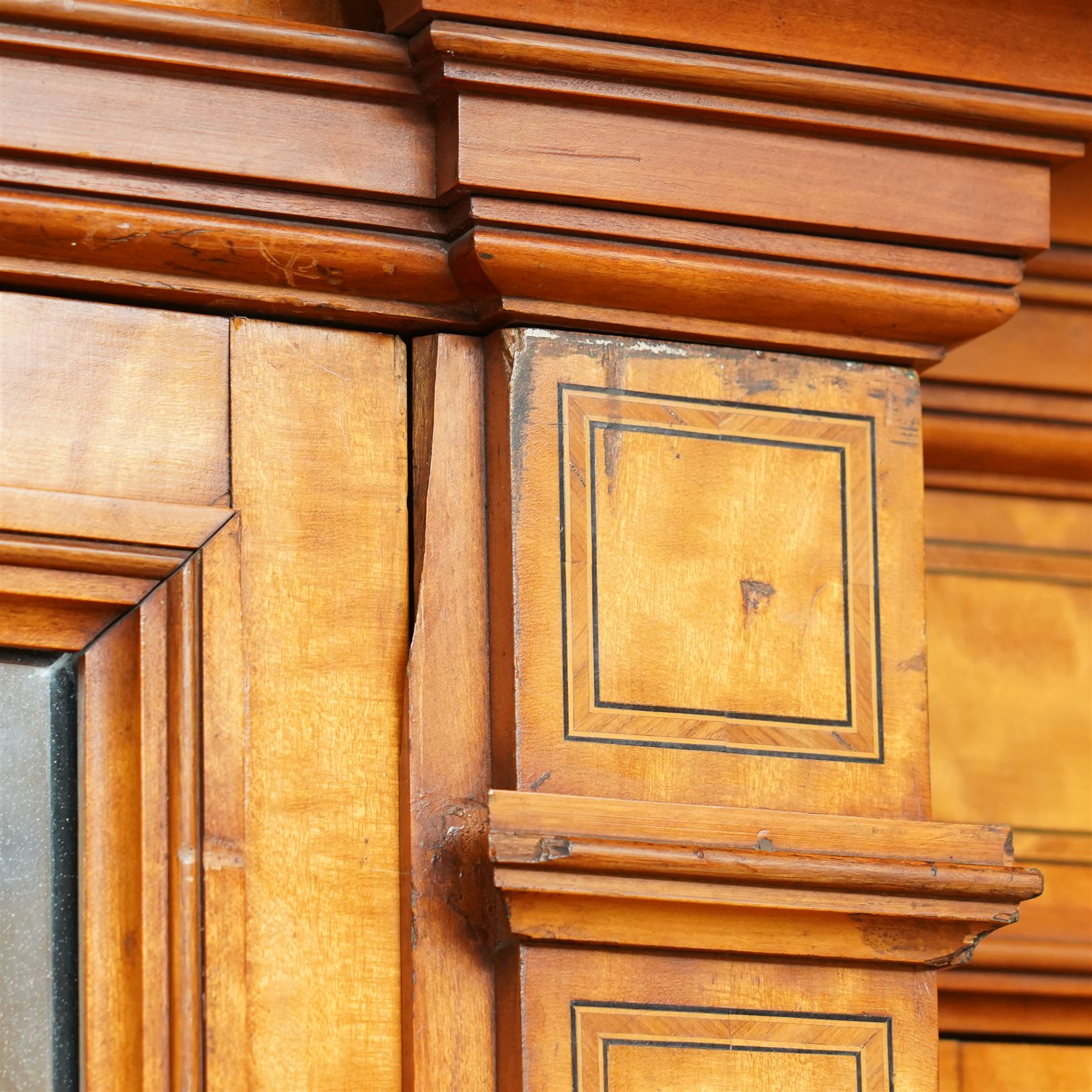 Victorian neoclassical style satinwood triple-section wardrobe, the central mirror section and arched pediment with carved monogram flanked by two panelled crossbanded doors, revealing two drawers and grooves for shelves, the hanging cupboards each with a single drawer, the whole supported on a plinth base