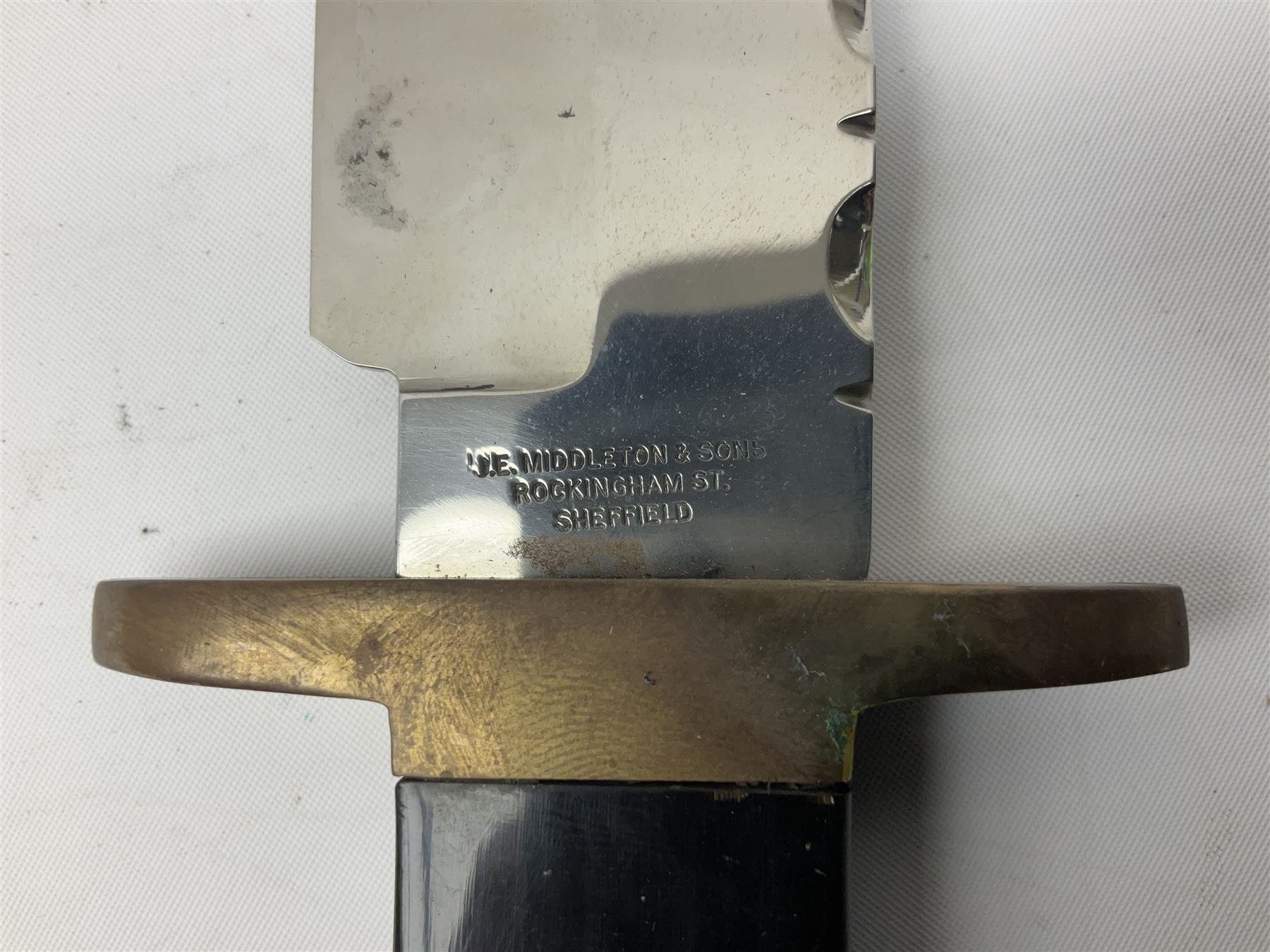 Large Bowie knife the 21cm steel blade marked J.E. Middleton & Sons Rockingham Street Sheffield with brass cross-piece and polished horn grip scales; in leather sheath L36cm overall