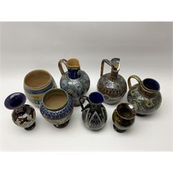 A collection of Doulton Lambeth, to include a jug with silver mounted rim, H18cm, a jug with relief flower head decoration upon a mottled blue ground, H24cm, a jardinaire with repeated foliate decoration, etc., each with impressed marks beneath. 
