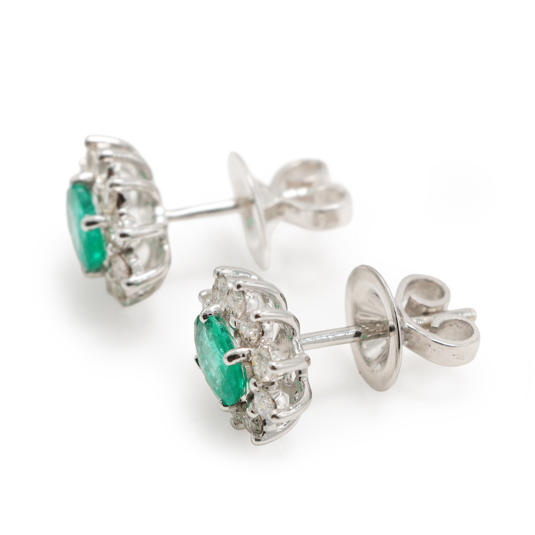 Pair of 18ct white gold emerald and diamond cluster earrings, each stud set with a single oval cut emerald surrounded by round brilliant cut diamonds, stamped, total emerald weight approx 0.75 carat, total diamond weight approx 0.55 carat