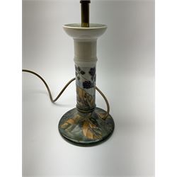 A Moorcroft table lamp, of candle stick form, decorated in the Blackberry and Leaves pattern upon a light blue ground, with impressed marks beneath, with accompanying cream shade with piped detail, overall H45cm.