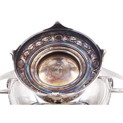 Art Nouveau silver twin handled rose bowl, with repousse rambling rose leaf border, inset with four blue circular enamel cabochons, upon footed pedestal with conforming border and four green oval enamel cabochons, hallmarked Walker & Hall, Sheffield 1908, including handles H13cm, approximate total weight 26.94 ozt (837.7 grams)