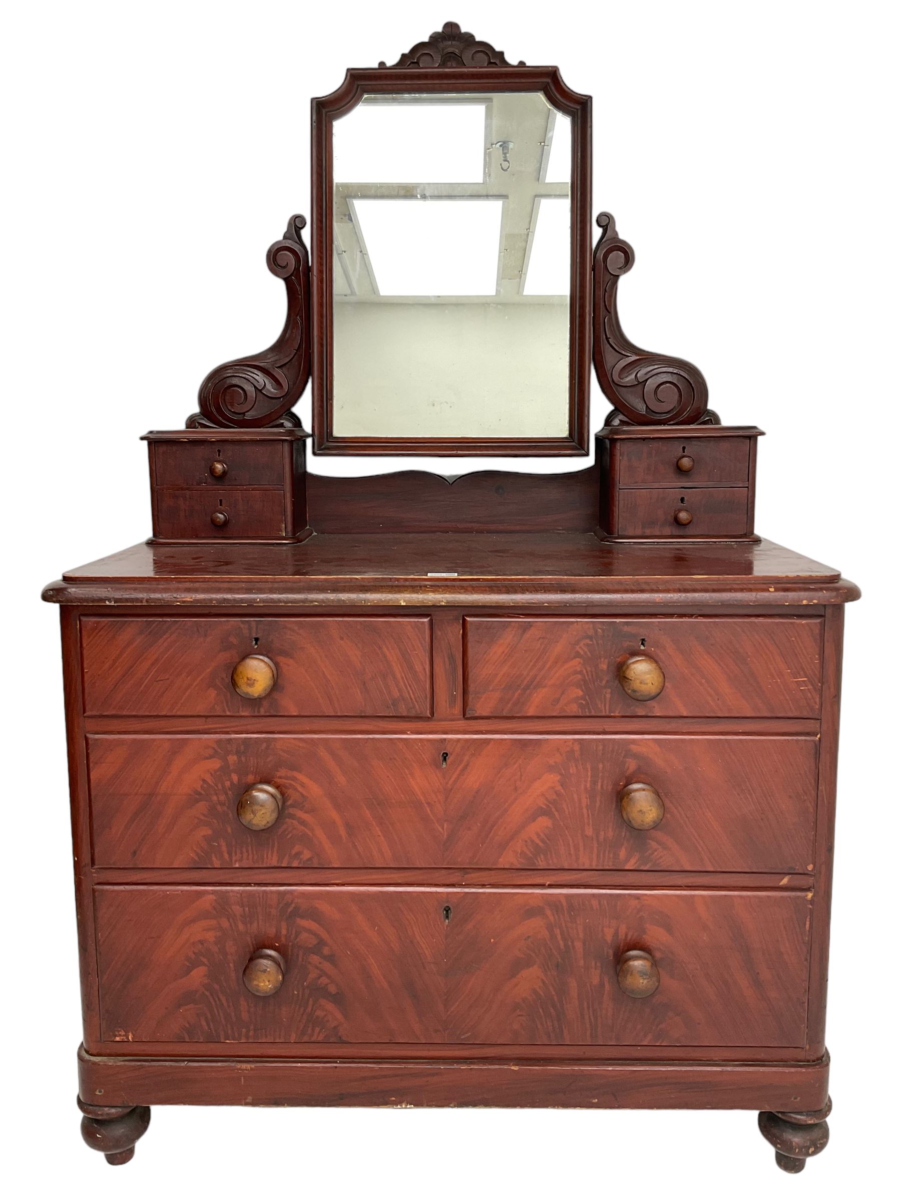 Victorian scumbled pine dressing chest, raised swing mirror in moulded frame with scrolled carved pediment, foliage S-scroll carved supports over trinket drawers, moulded rectangular top with rounded corners over two short and two long drawers, skirted base on turned feet, scumbled to resemble mahogany 