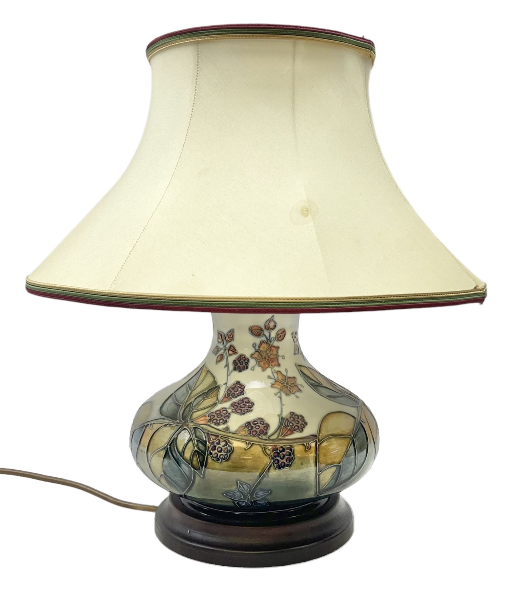 Moorcroft table lamp of squat baluster form, decorated in the Autumn Blackberry, with Moorcroft cream fabric shade with gold, green and red piping, overall H38cm