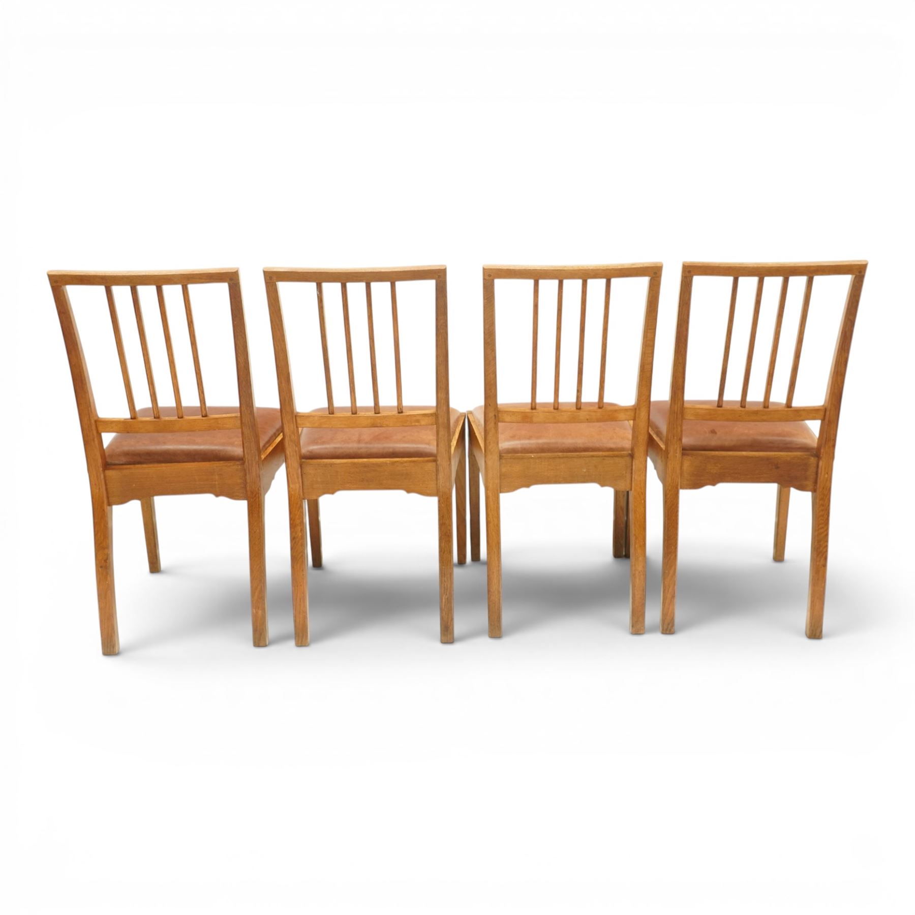 Acornman - set of four oak dining chairs, chamfered slatted back, tan leather drop in seat, raised on square supports with carved acorn signature, by the workshop of Alan Grainger of Brandsby