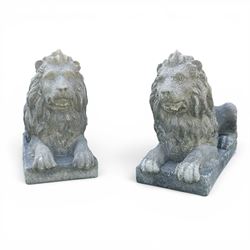 Pair of large cast stone recumbent garden male lions, modelled with flowing manes and rais...