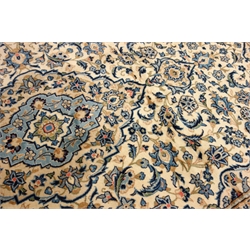  Persian Kashan ivory ground rug, blue scrolled foliage field with medallion, repeating guarded border, 303cm x 194cm  
