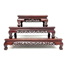 Set of three Chinese rosewood graduating stands, carved and pierced rails, shaped bracket supports 