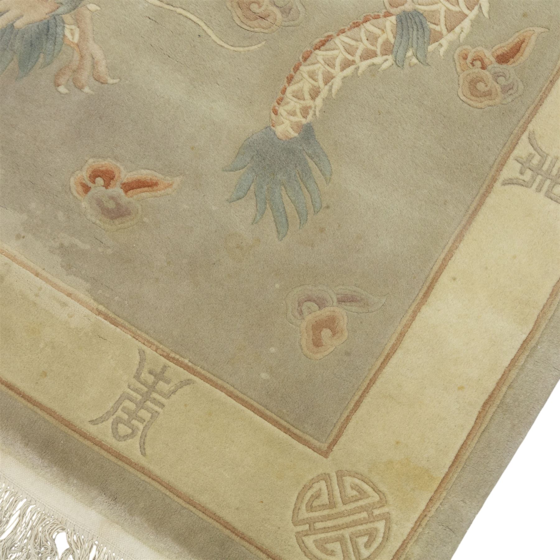 Chinese wool rug, the pale grey central field decorated with two stylised dragons, flaming pearls and cloud scrolls, within a cream border of shou medallions and geometric motifs, with cotton fringe ends