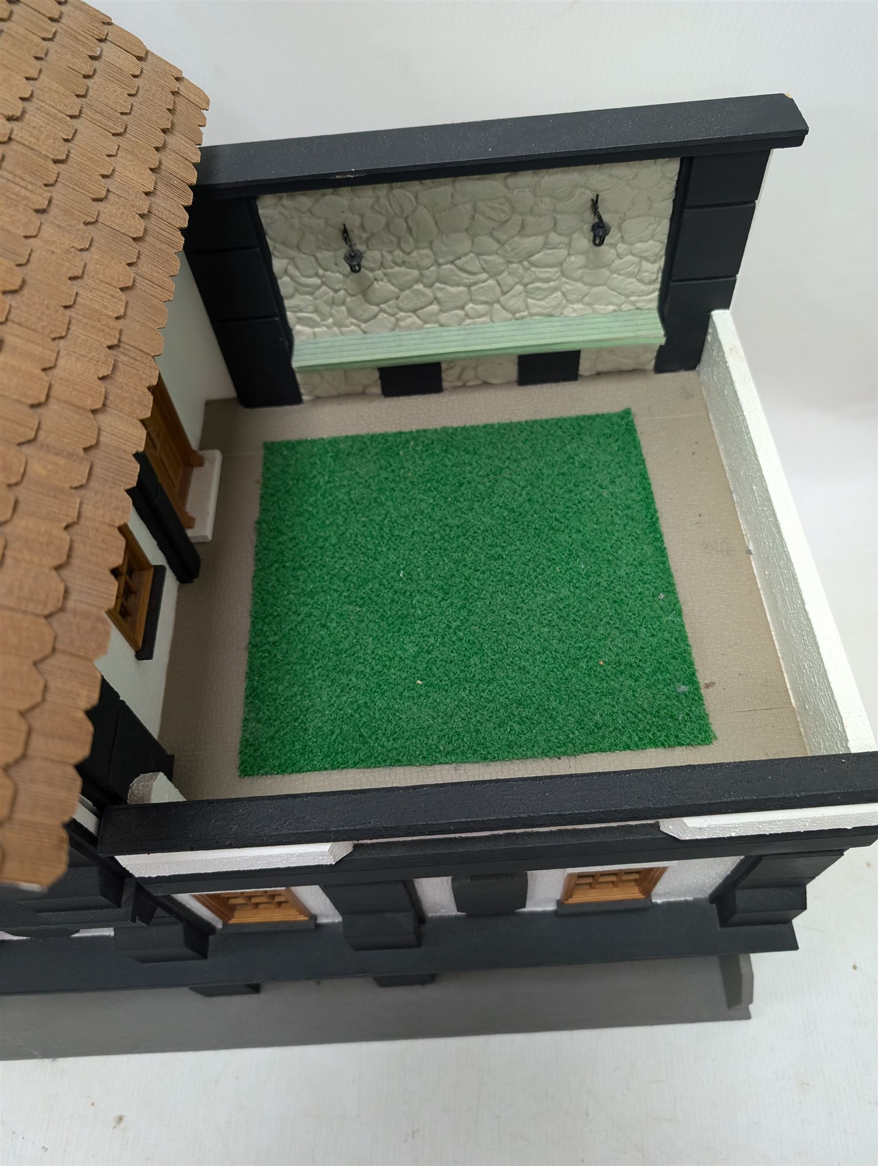 1:24 scale four-storey tudor-style dolls house, with black and white exterior, balcony garden, glazed panelled windows and wooden shingle roof, with decorated interior and wired fireplaces and lighting, H65cm, W58cm, D31cm, 