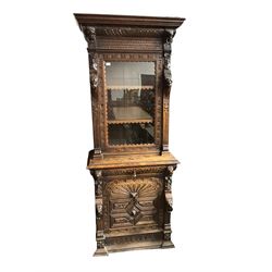 Victorian heavily carved oak cabinet, projecting cornice over gadroon frieze, lion mask and figure carved uprights, the single glazed cupboard fitted with three shelves, above single drawer and lower cupboard enclosed by panelled door with geometric mouldings and masks 
