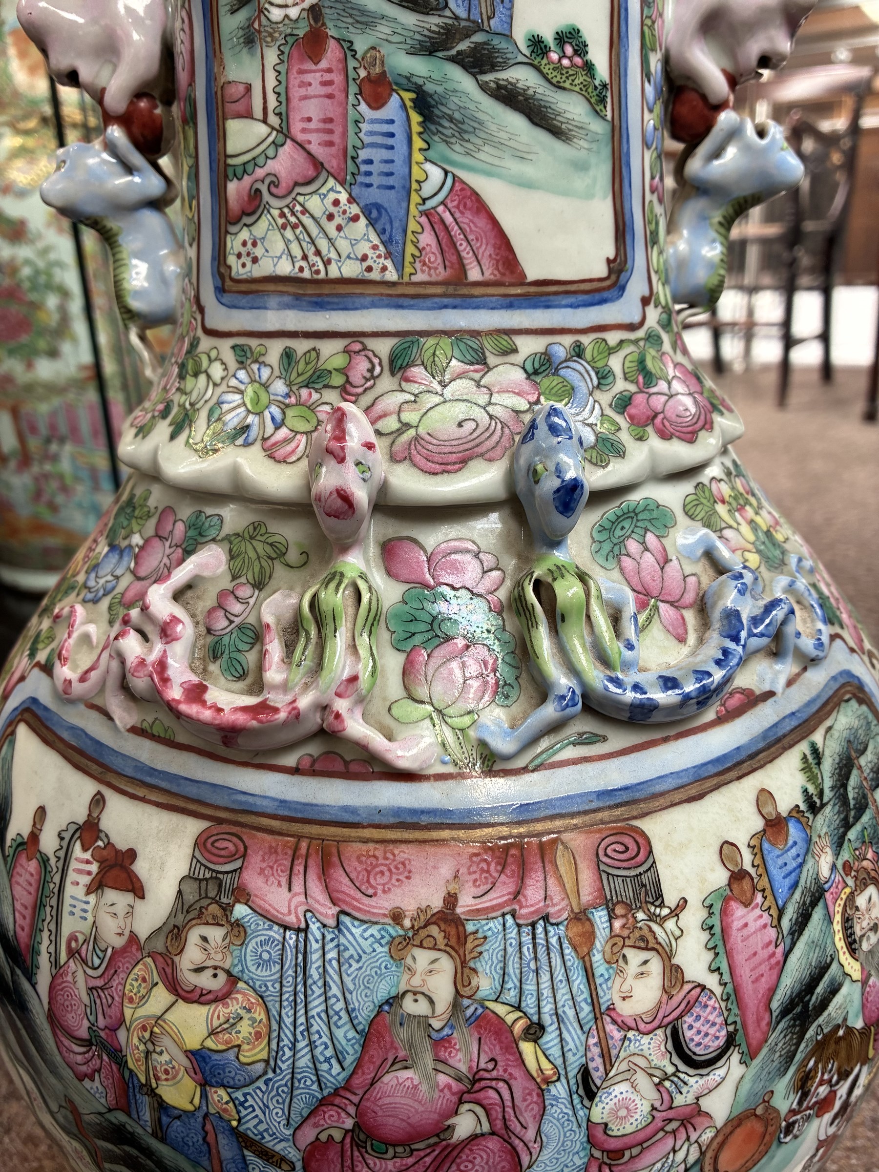 Large pair of 19th century Cantonese famille rose vases, each painted with various courtly scenes, including a display of warriors fighting on horseback before an official and his attendants, double Buddhist lion handles and applied at the shoulders with chilong, the lower band painted with Greek key motif, H58cm (2)