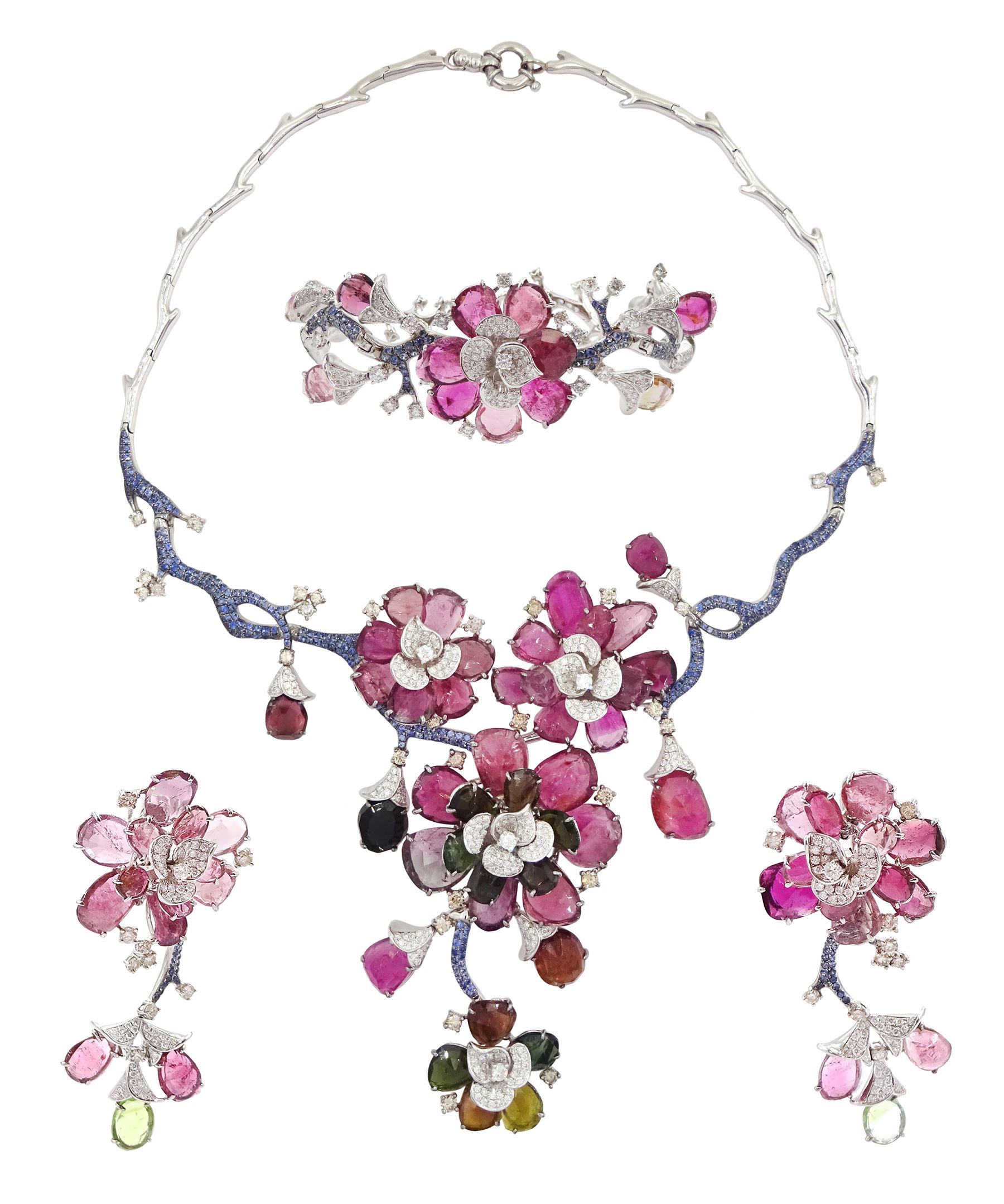 18ct white gold gemstone set floral jewellery suite, comprising necklace, pair of earrings and bracelet, each with tourmaline flower petals, round brilliant cut diamond centres and sapphire stems, stamped